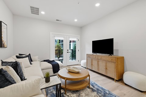 A living room with a white couch, a wooden coffee table, and a flat screen TV.