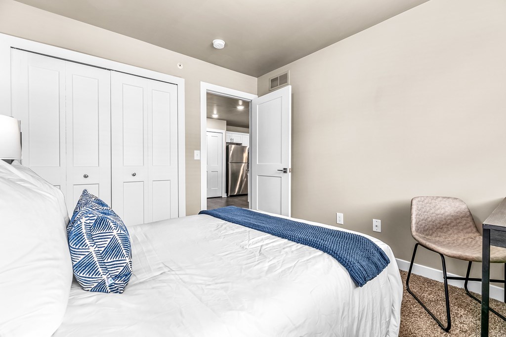 A bedroom with a white bed and a blue pillow.
