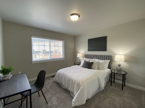 a bedroom with a bed and a desk and a window