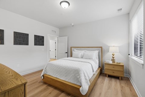 A bedroom with a bed, nightstand, and two wall hangings.