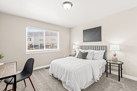 A bedroom with a bed, chair, and window.