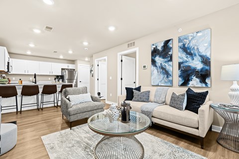 A modern living room with a glass coffee table and a grey sofa.