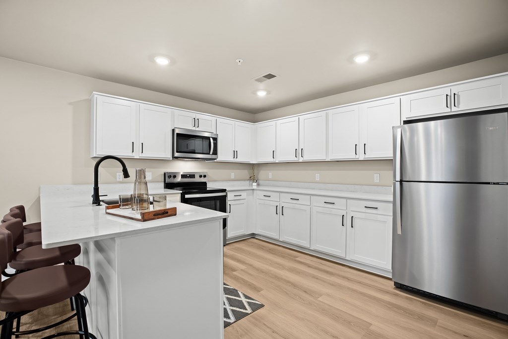 A modern kitchen with white cabinets and a stainless steel refrigerator.