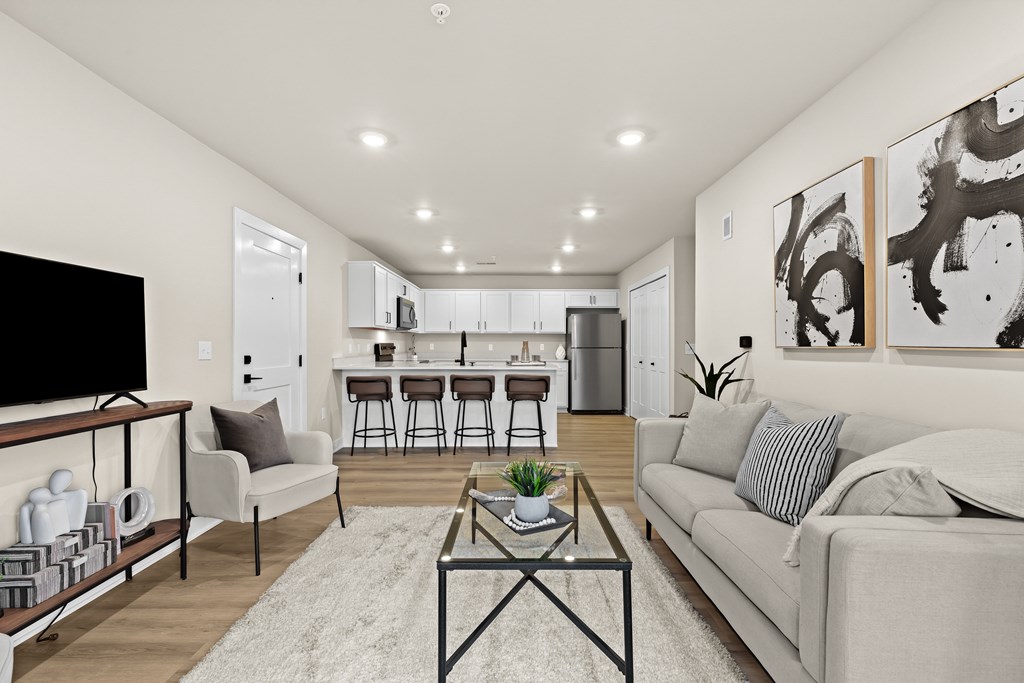 A modern living room with a grey couch, a coffee table, and a bar area in the background.