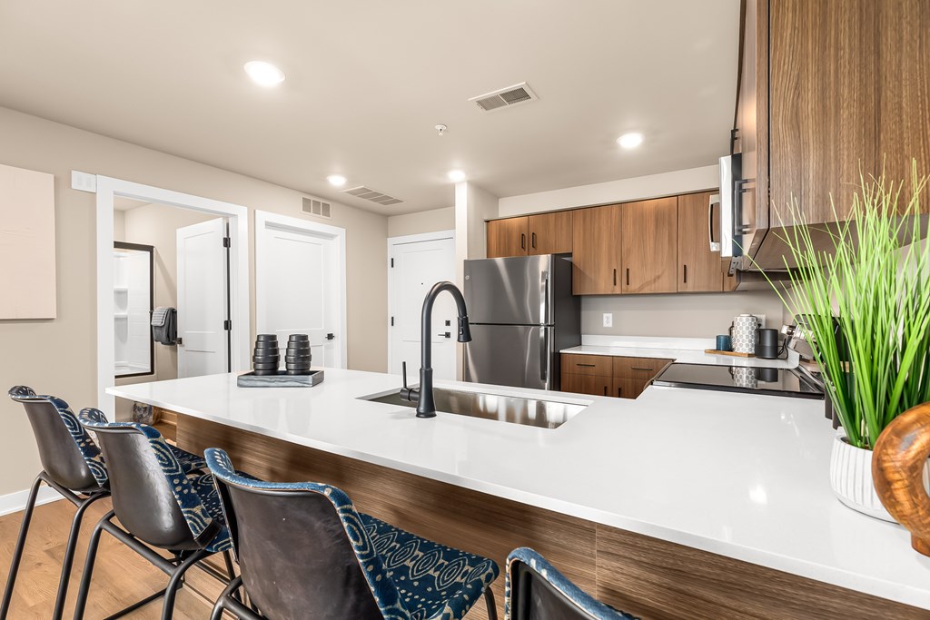 A modern kitchen with a white countertop and a stainless steel refrigerator.