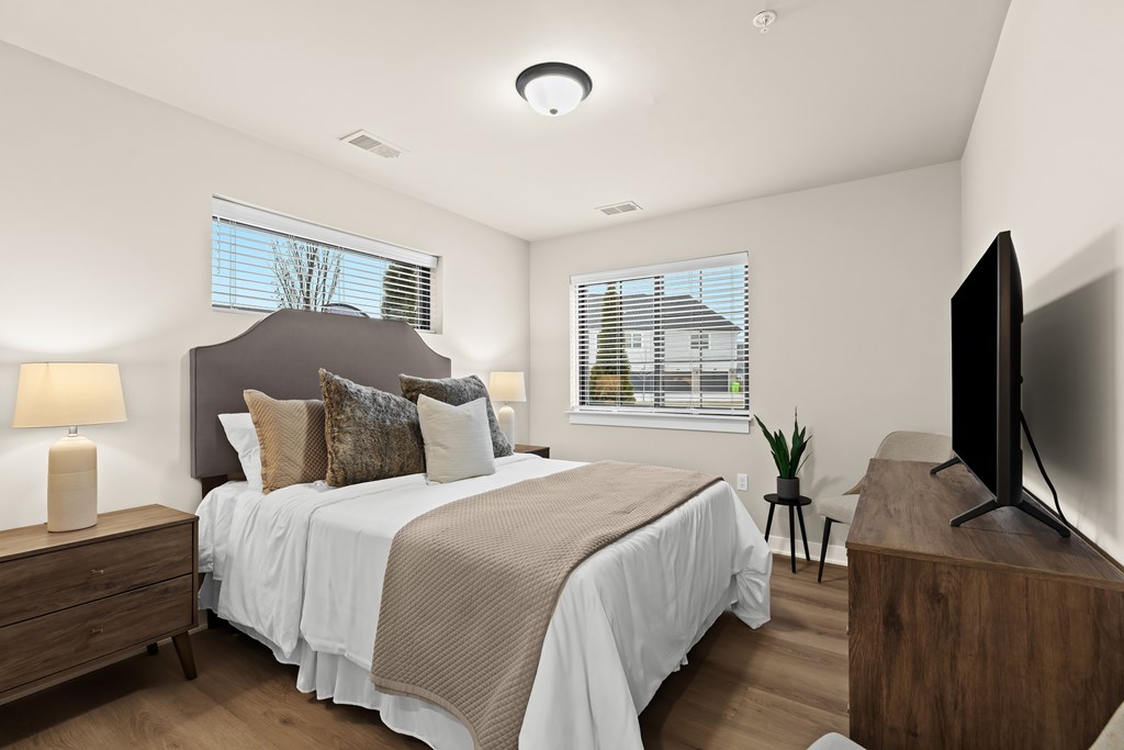 A bedroom with a large bed, a television, and a window with blinds.