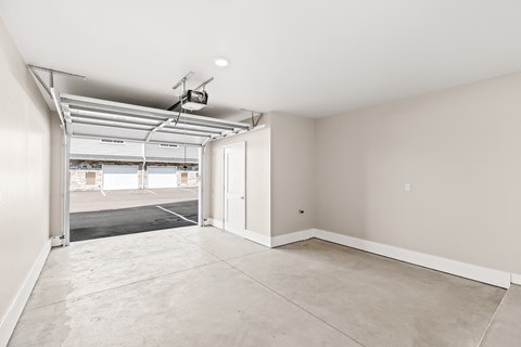 A spacious room with a garage door open to a parking lot.
