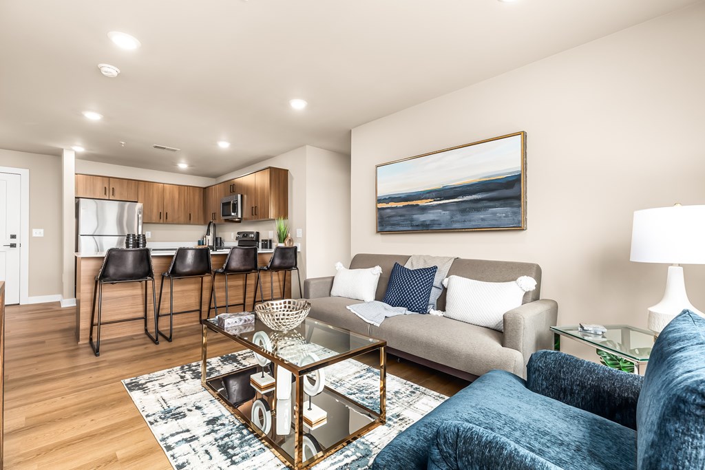 A living room with a grey couch and a painting on the wall.