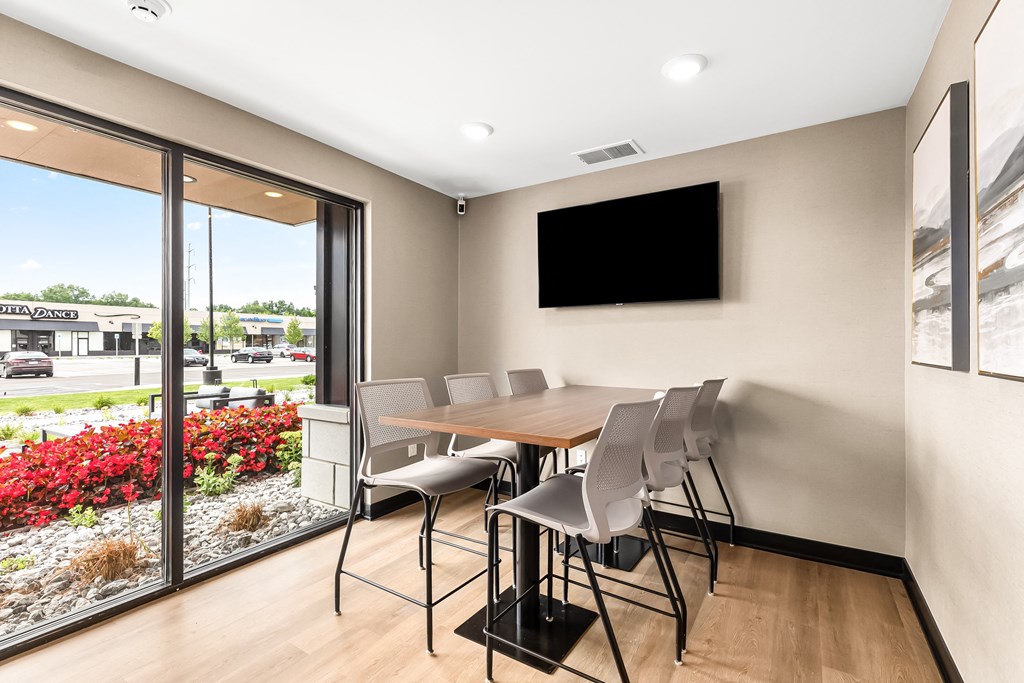 a meeting room with a table and chairs and a flat screen tv