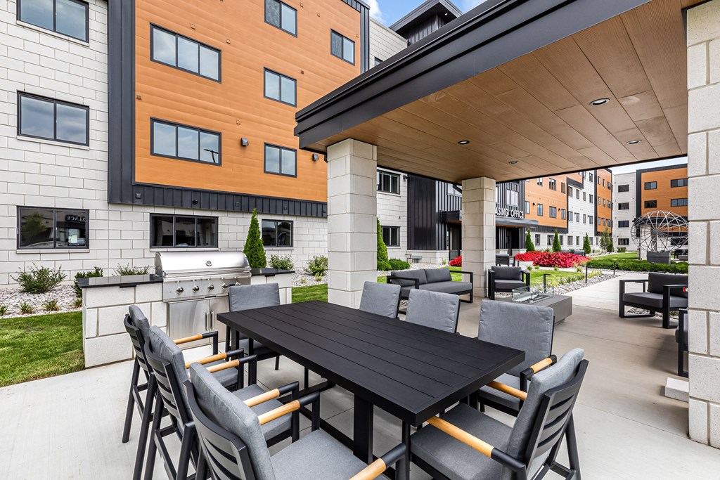 a patio with a table and chairs and a grill