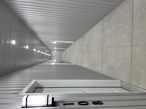 A long, narrow corridor with a metal roof and concrete walls.