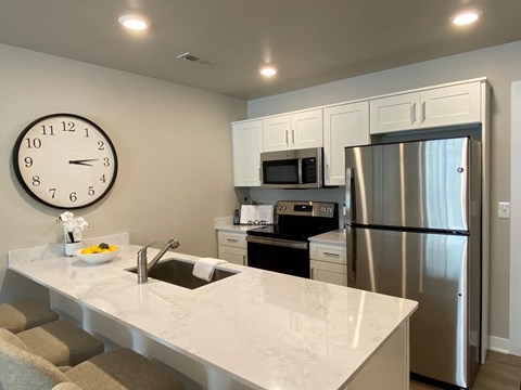a kitchen with a large quartz counter top and a stainless steel refrigerator