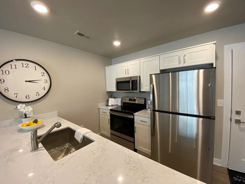 a kitchen with stainless steel appliances and a large clock on the wall