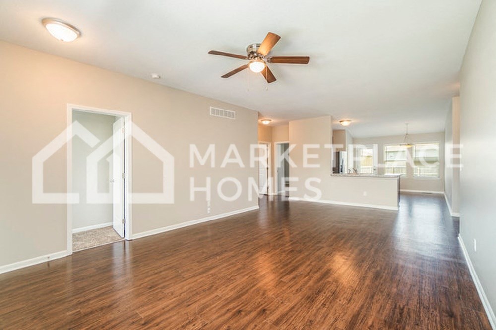 a spacious living room with a ceiling fan and hard wood floors