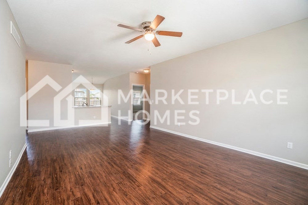 an empty living room with a ceiling fan and