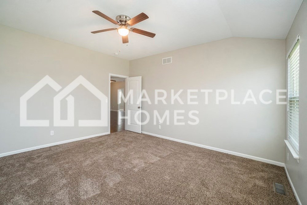 an empty living room with a ceiling fan and