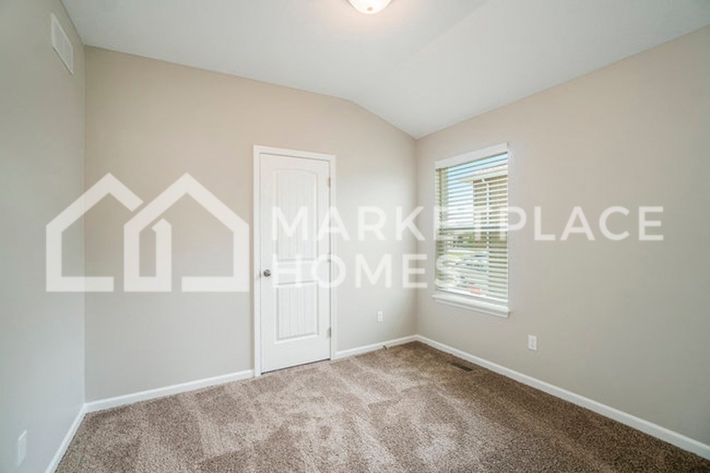 an empty living room with carpet and a white door
