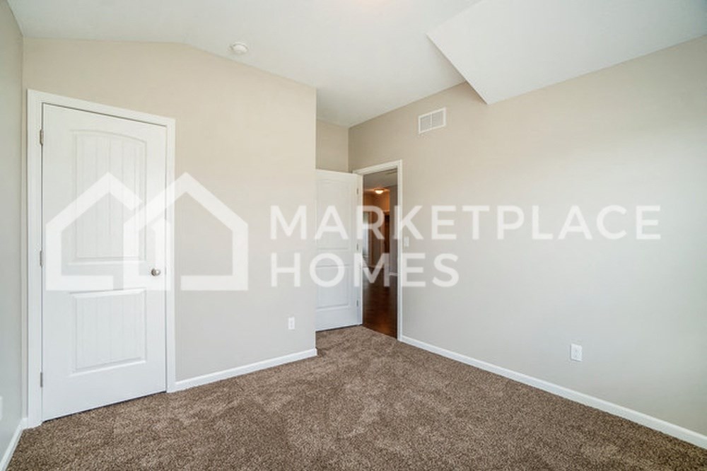 a bedroom with a white door and a carpeted floor