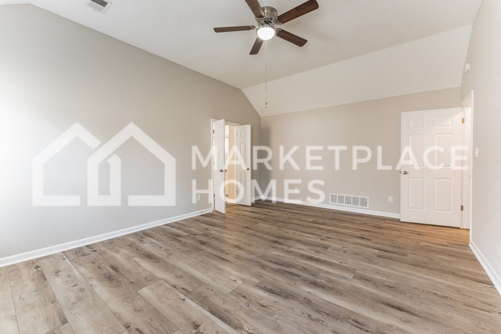 a spacious living room with hardwood floors and a ceiling fan