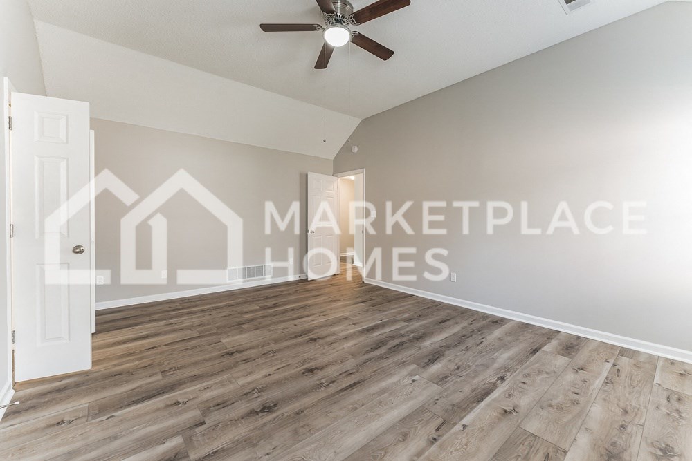 a spacious living room with hardwood flooring and a ceiling fan
