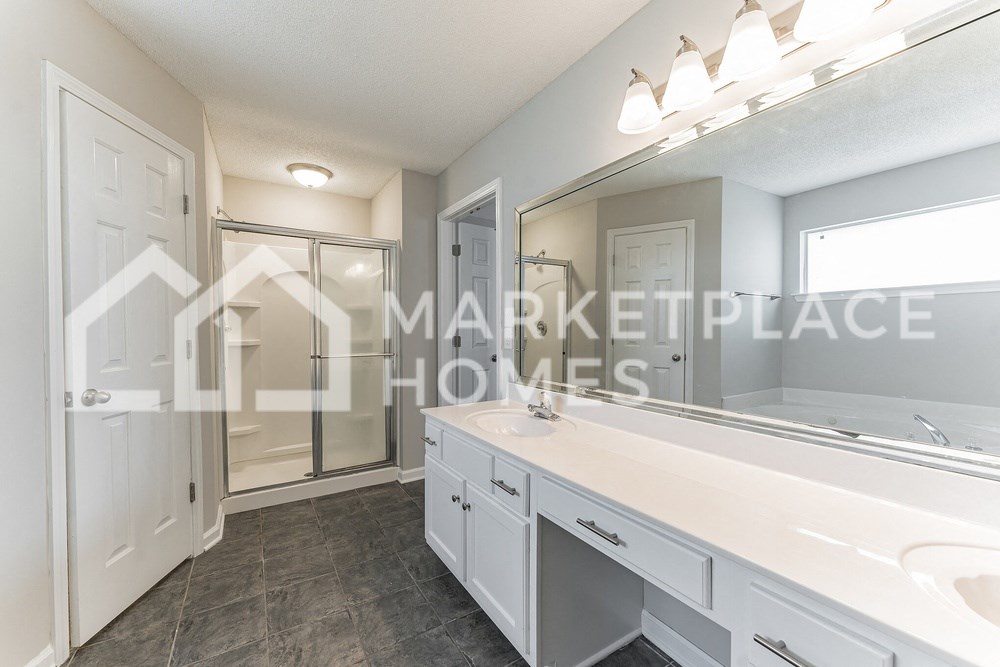 a renovated bathroom with white cabinets and a large mirror