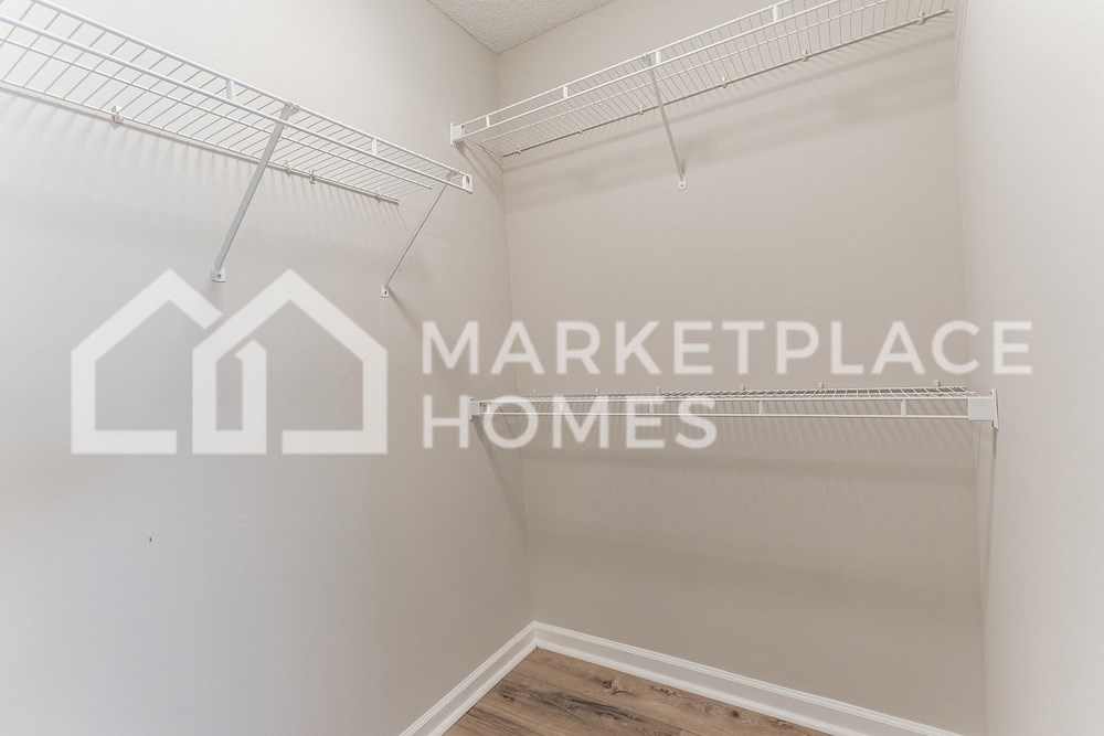 a walk in closet in a home with the marketplace homes logo on it