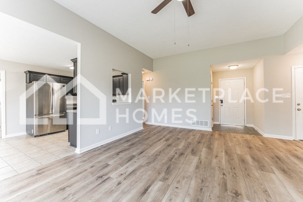 a renovated living room with hardwood flooring and a large room with a kitchen