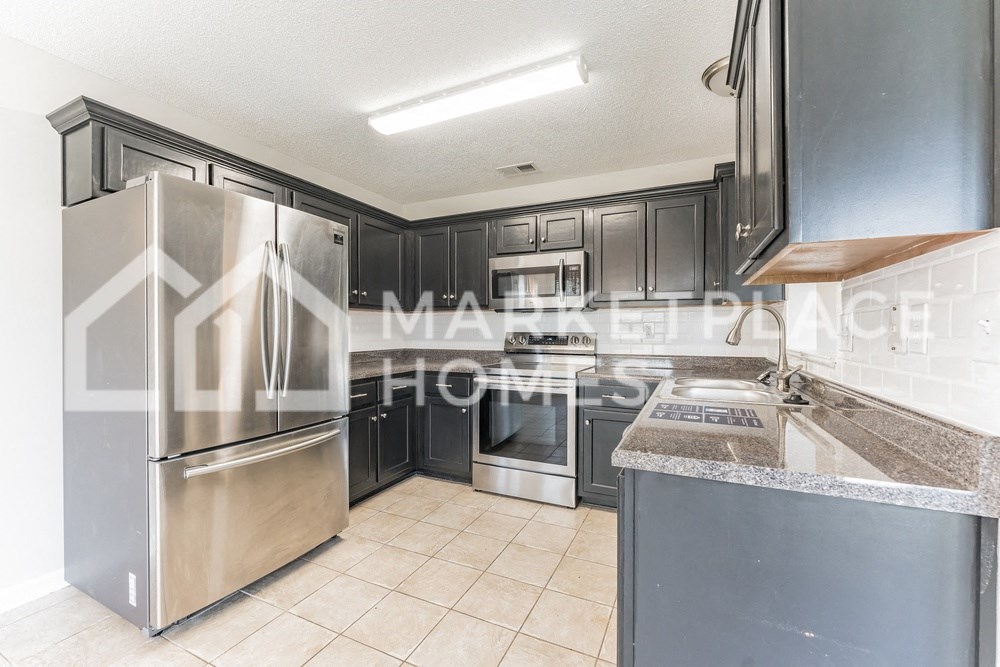a kitchen with black cabinets and stainless steel appliances