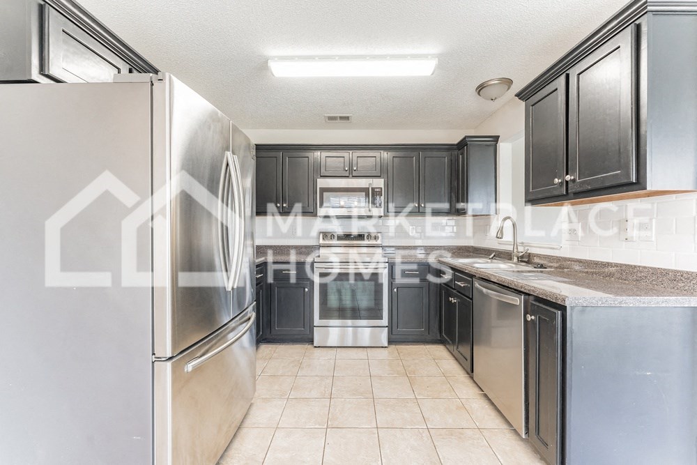 a kitchen with stainless steel appliances and black cabinets