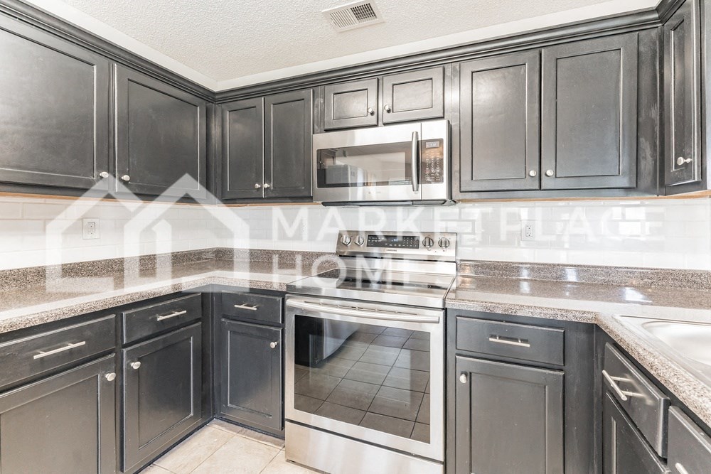a kitchen with black cabinets and stainless steel appliances