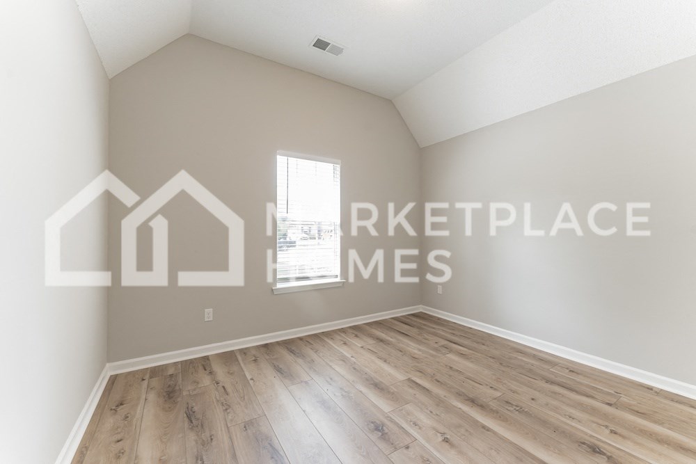 an empty room with hardwood floors and a window