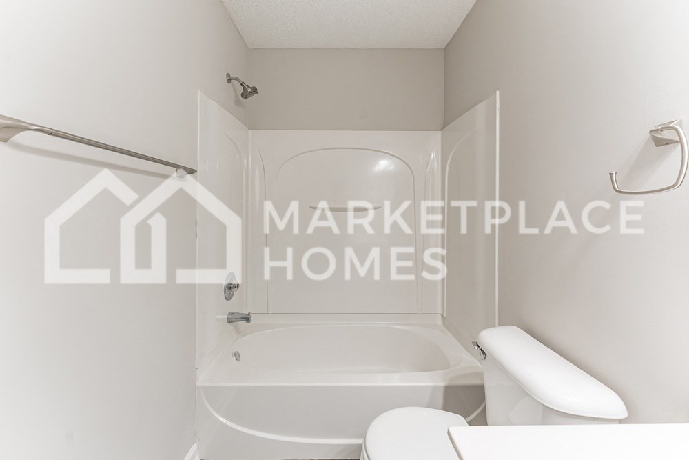 a white bathroom with a white toilet and a bath tub