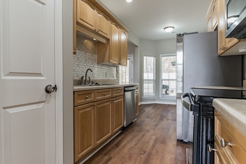 a kitchen with wooden cabinets and stainless steel appliances and a window