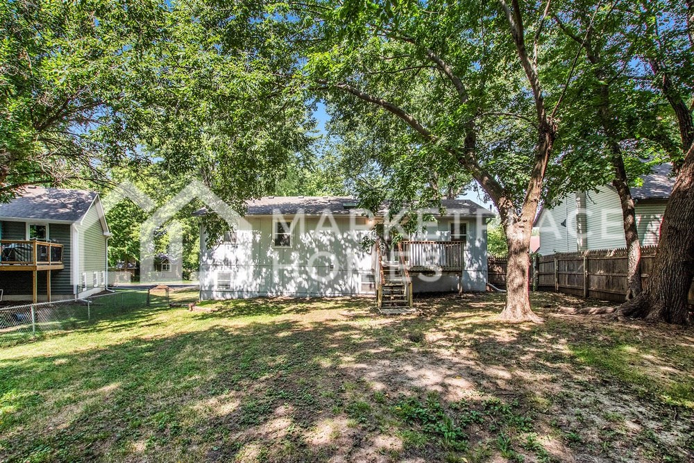 a white house with a yard with trees and a fence