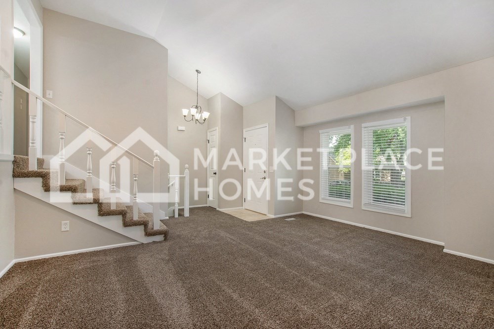 a sizable living room with a staircase and a carpeted floor