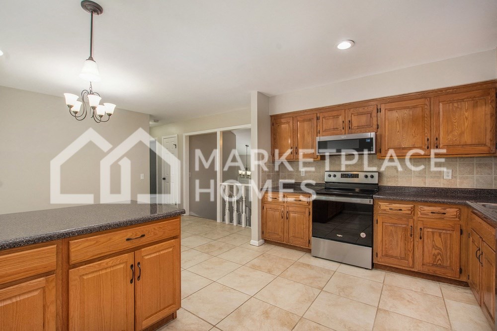 a large kitchen with wooden cabinets and tiled floors