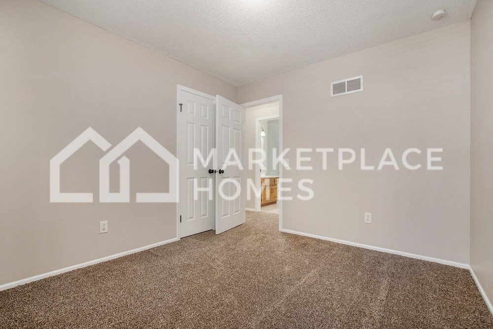 a bedroom with a door to a closet and a carpeted floor