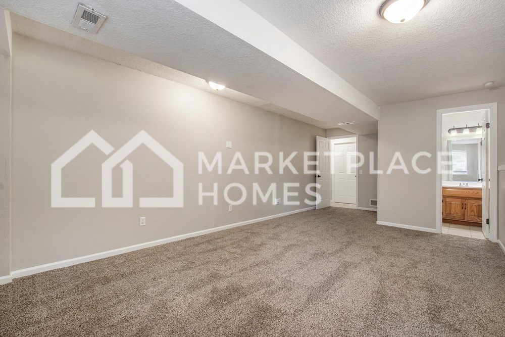 a spacious living room with carpet and a door to the bathroom