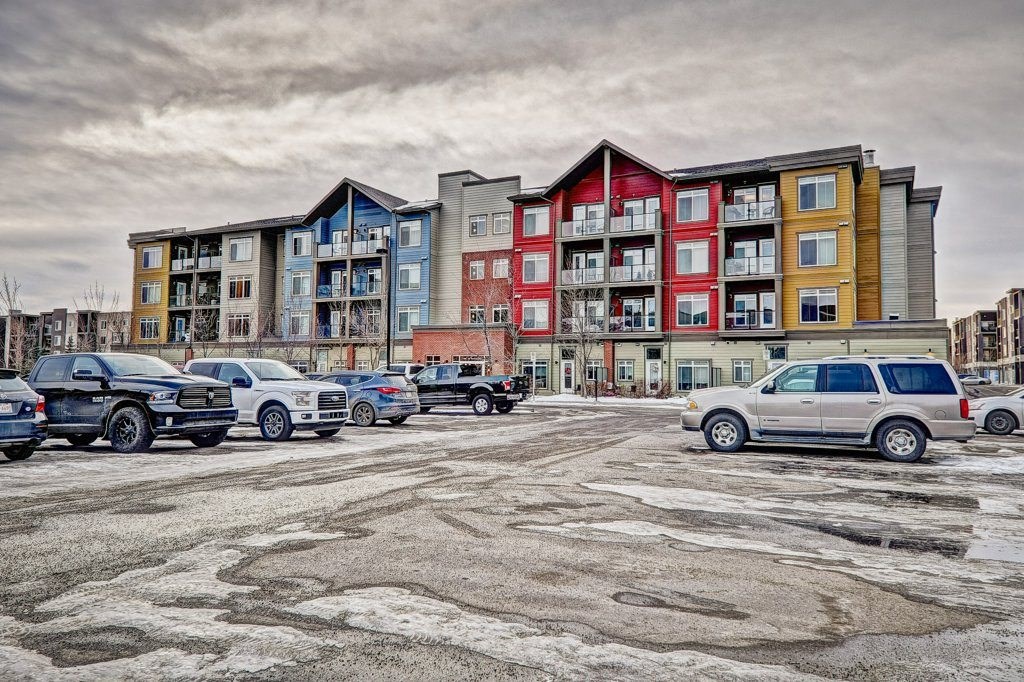 A parking lot with cars and a multi-story apartment building in the background.