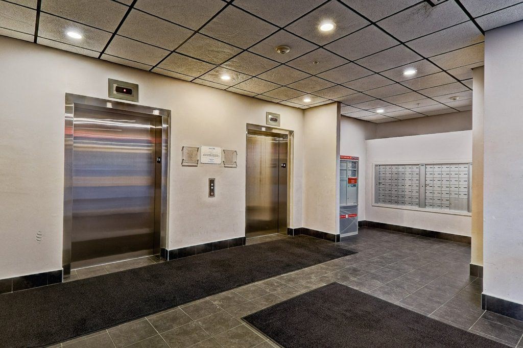 A hallway with two elevators and a calendar on the wall.