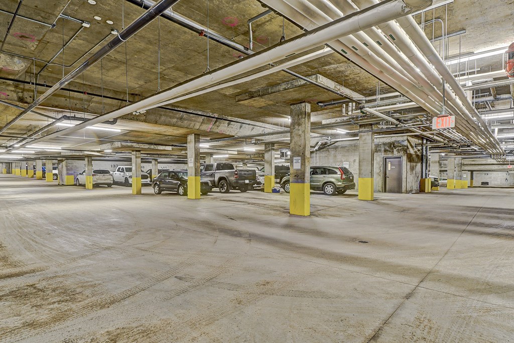 A parking garage with cars parked and yellow poles.