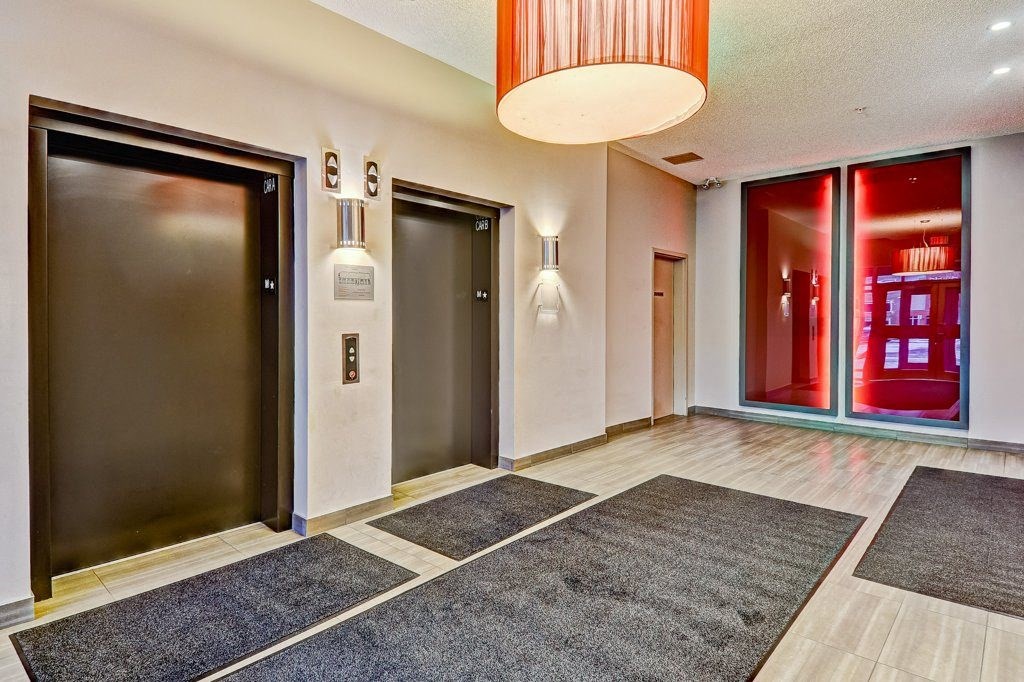 A hallway with a red light and a black door.
