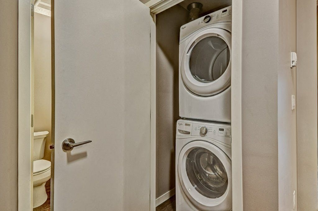 A white door opens to a small laundry room with a washer and dryer.