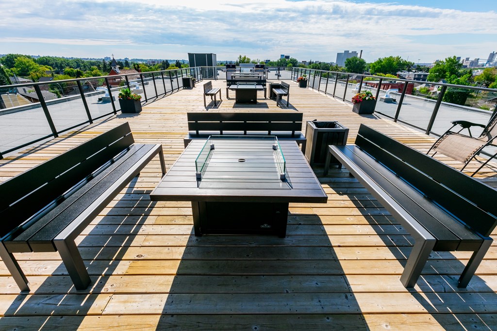 A wooden deck with benches and a table overlooking a cityscape.
