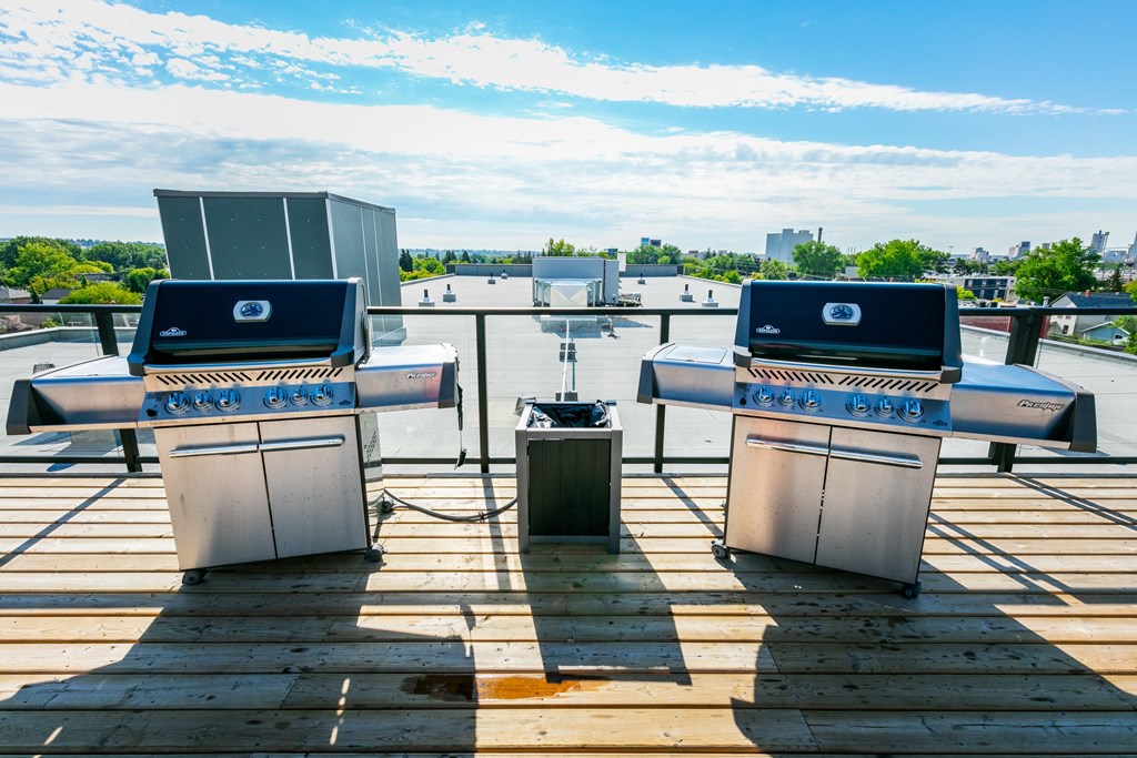 A rooftop with four grills and a table in the middle.