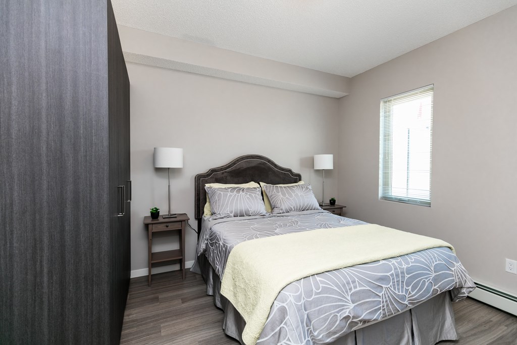 A bedroom with a large bed and a nightstand with a lamp.