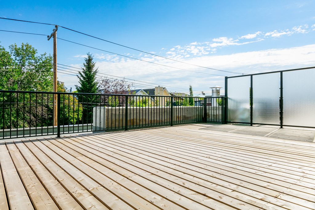 A wooden deck with a black fence and a clear blue sky.