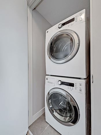 Two white front loading washing machines in a small laundry room.