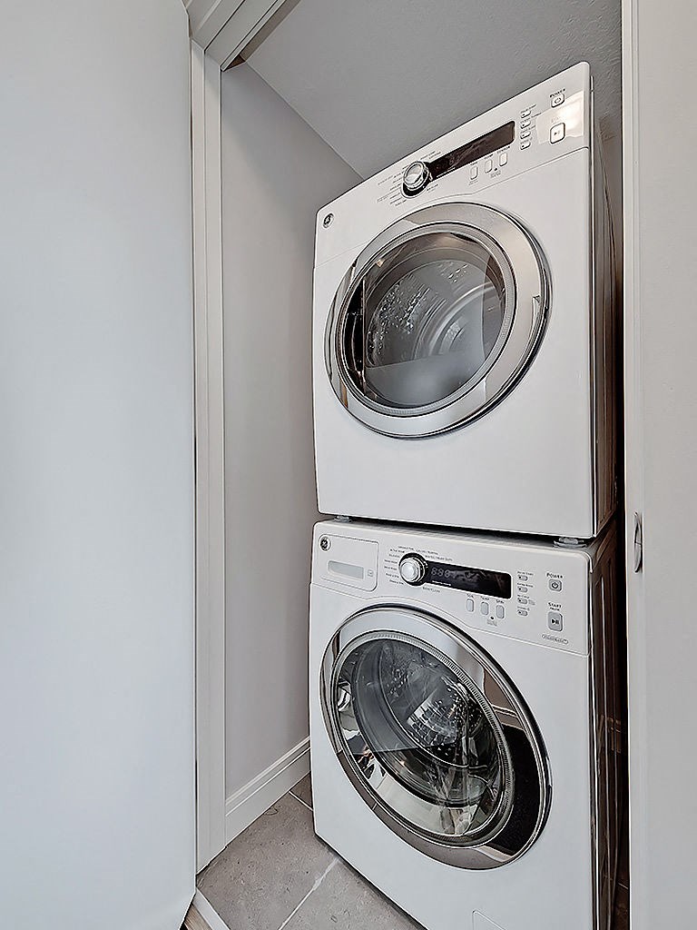 Two white front loading washing machines in a small laundry room.