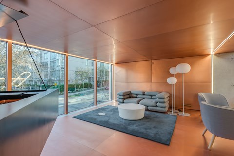 A modern living room with a large window and a grey sofa.